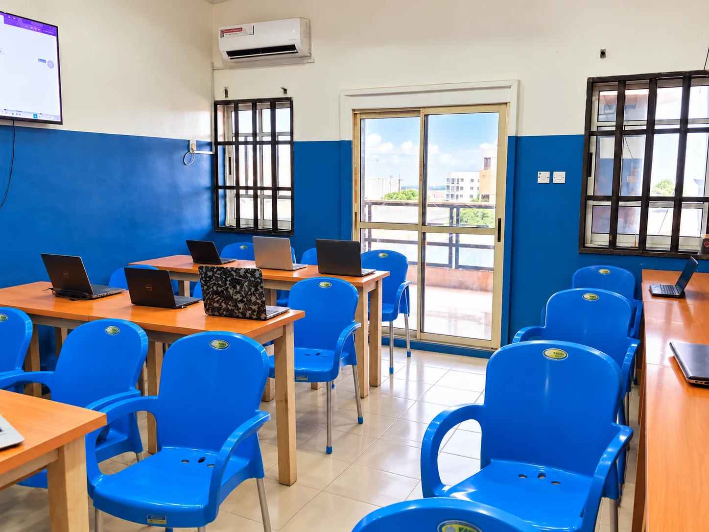 Classroom with blue chairs, wooden desks and laptops