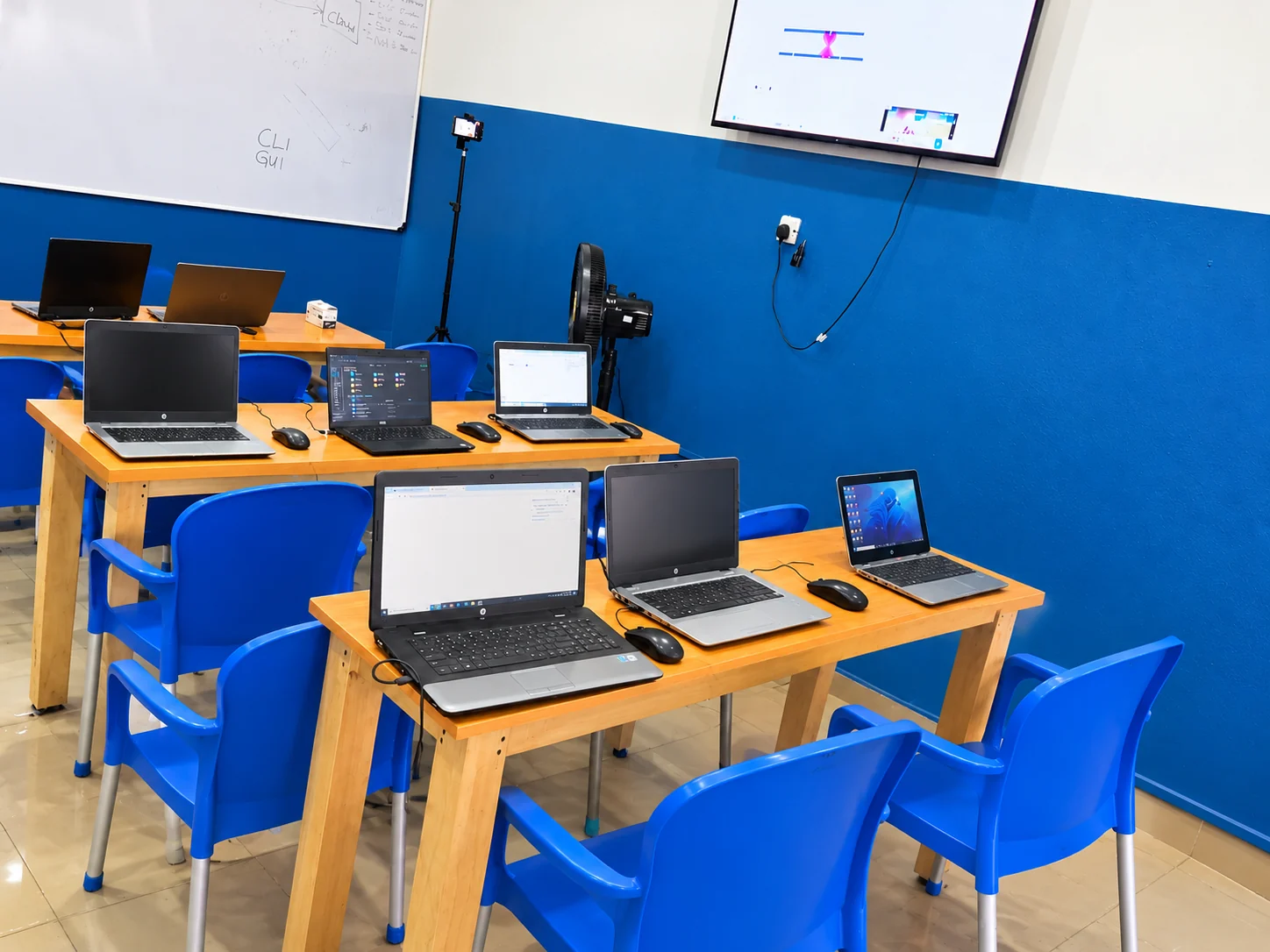 Laptop workstations facing a whiteboard and teaching screen